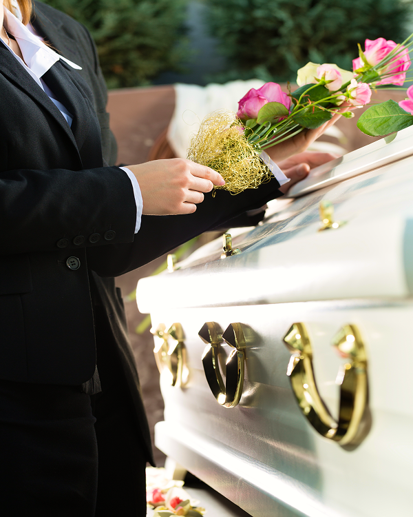 funeral director arranging flowers on coffin